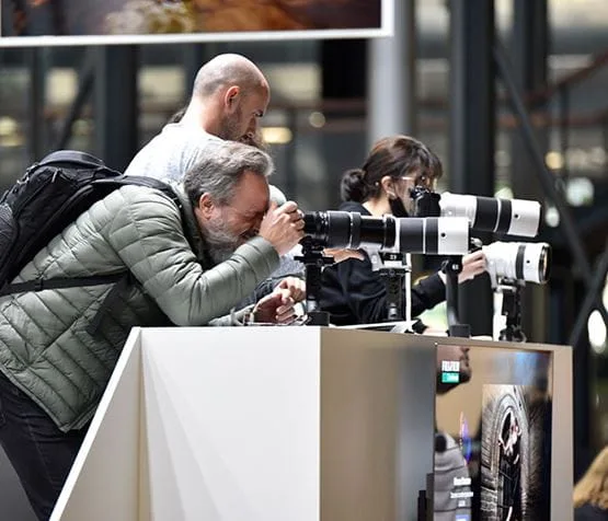 Un visiteur testant un téléobjectif photo au salon de la photo à Paris