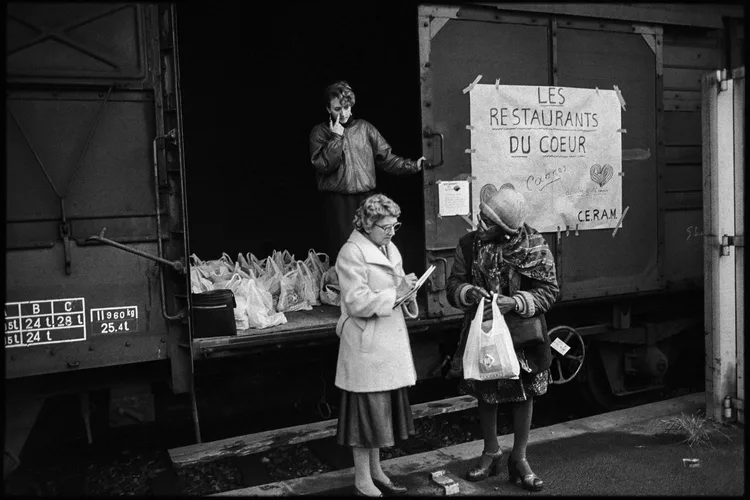 Volontaires des Restaurants du Coeur distribuant des sacs de nourriture depuis un train de la SNCF à Cannes Décembre 1985 (Photo by Christophe SIMON / AFP)